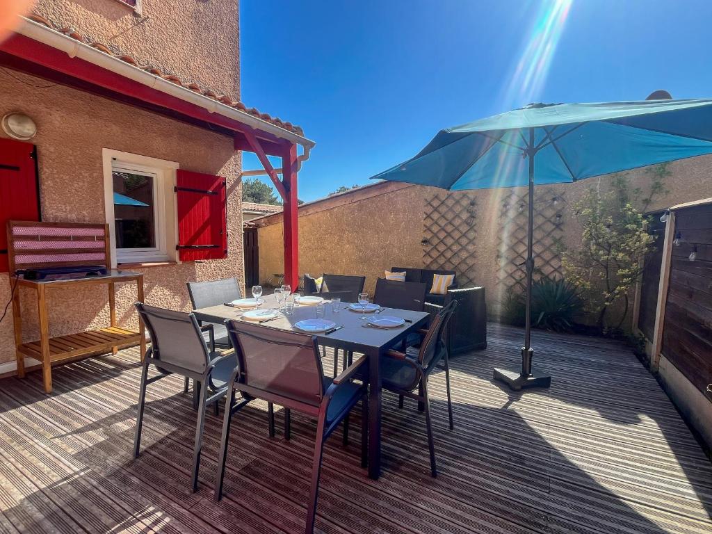 a table with chairs and an umbrella on a deck at Palombes 5 in Lacanau