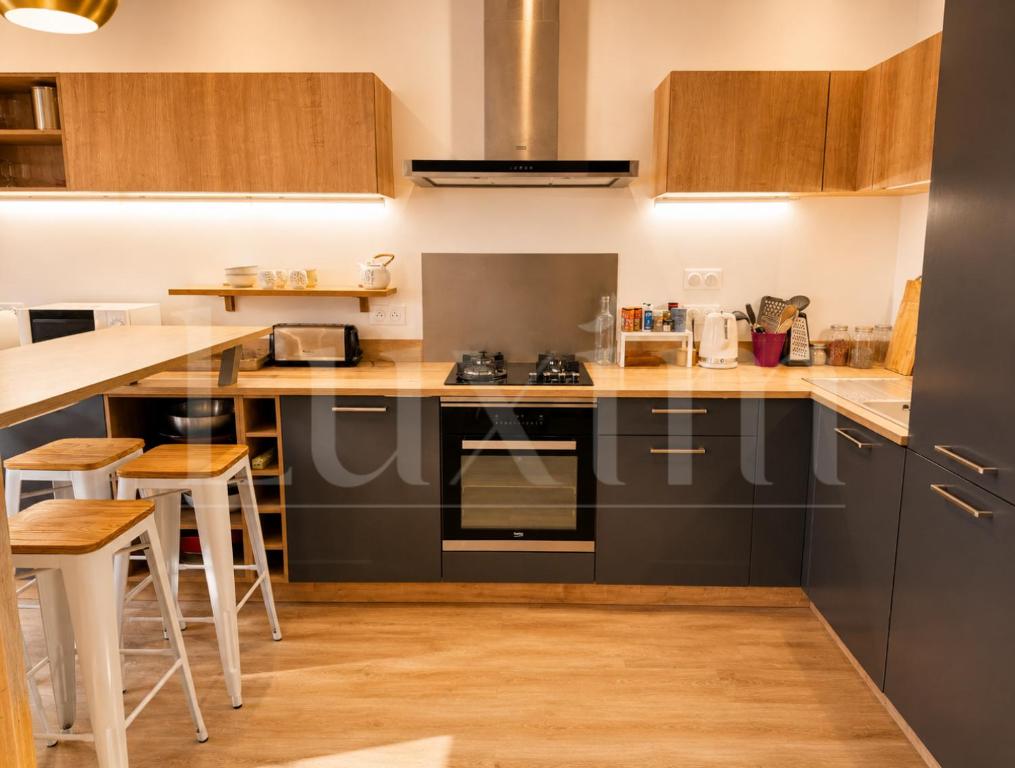 a kitchen with black appliances and wooden cabinets at Le Cocon de la Presqu'île in Lyon