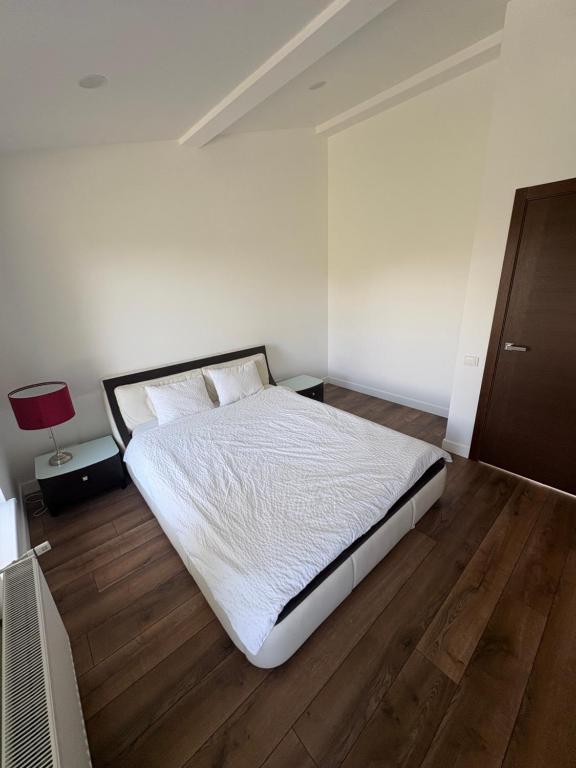 a bedroom with a bed with white sheets and wooden floors at Jasmine Guest Room in Jauntīreļi