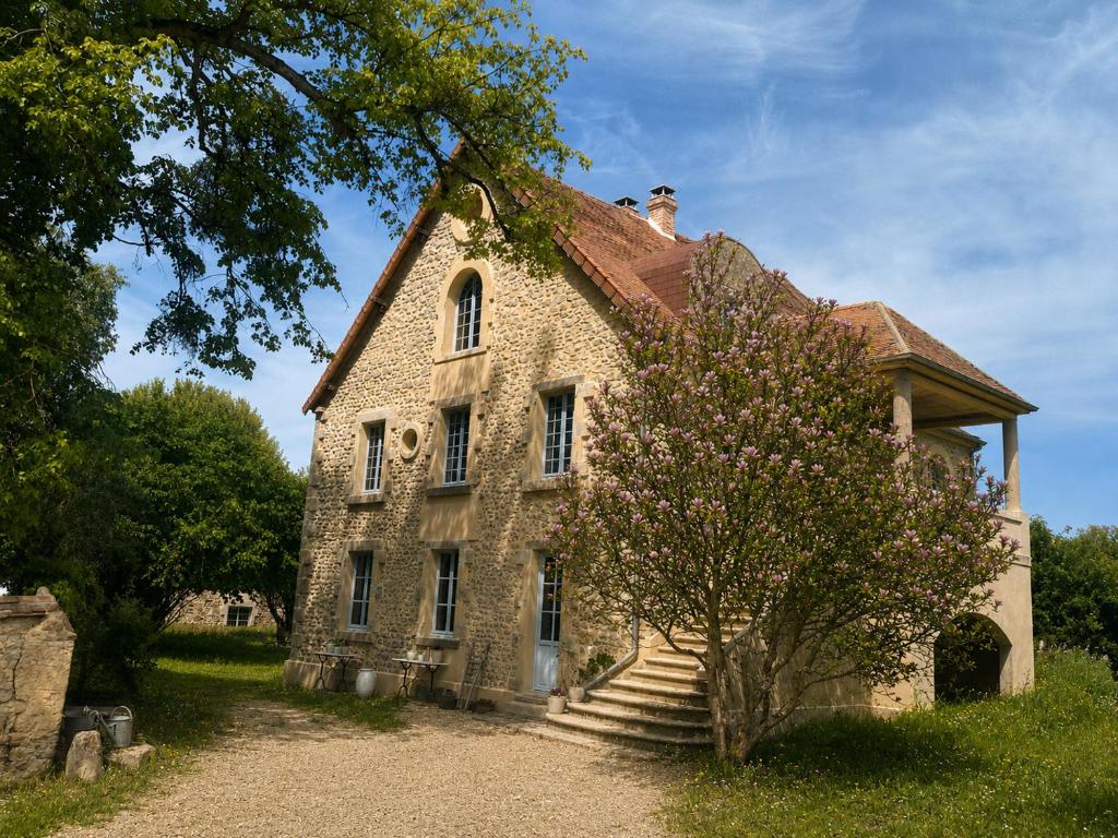 an old stone house with a tree in front of it at La Petite Noble in Commentry