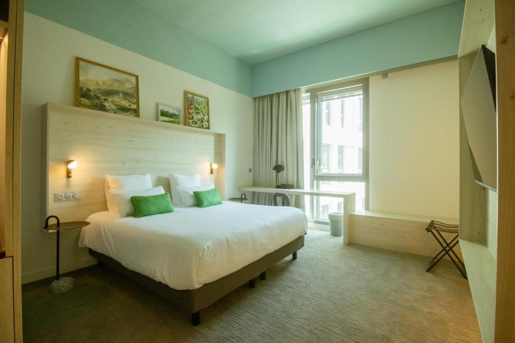 a bedroom with a large white bed with green pillows at Ysotop Hôtel Grenoble in Grenoble