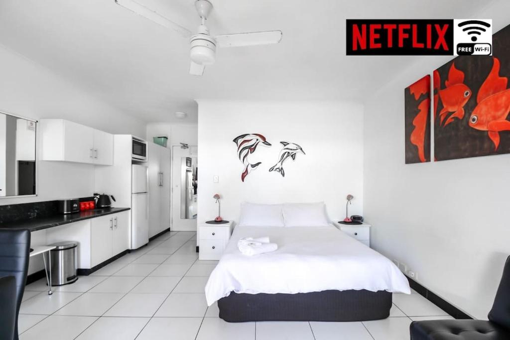 a white bedroom with a bed and a kitchen at DHR U120 - The Oceana in Eimeo
