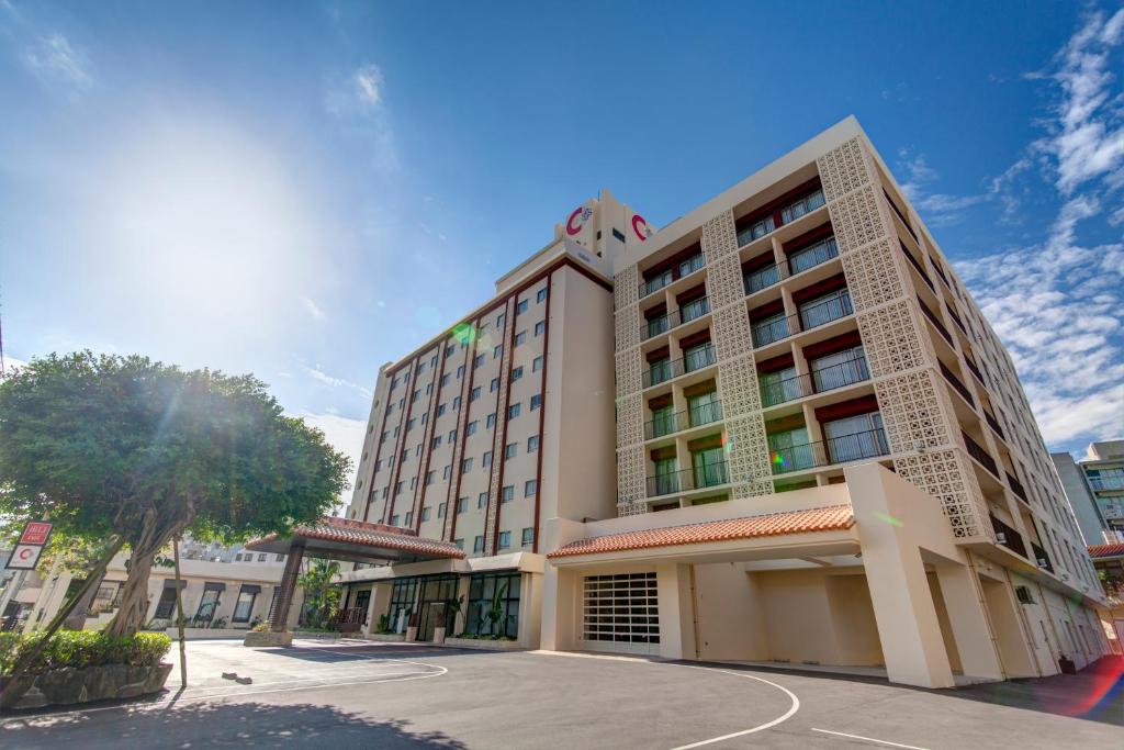 un edificio de hotel con un árbol delante de él en Community & Spa Naha Central Hotel, en Naha