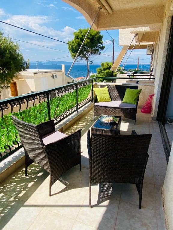 a patio with chairs and tables and a view of the ocean at Peaceful Seaside Apartments in Vaia