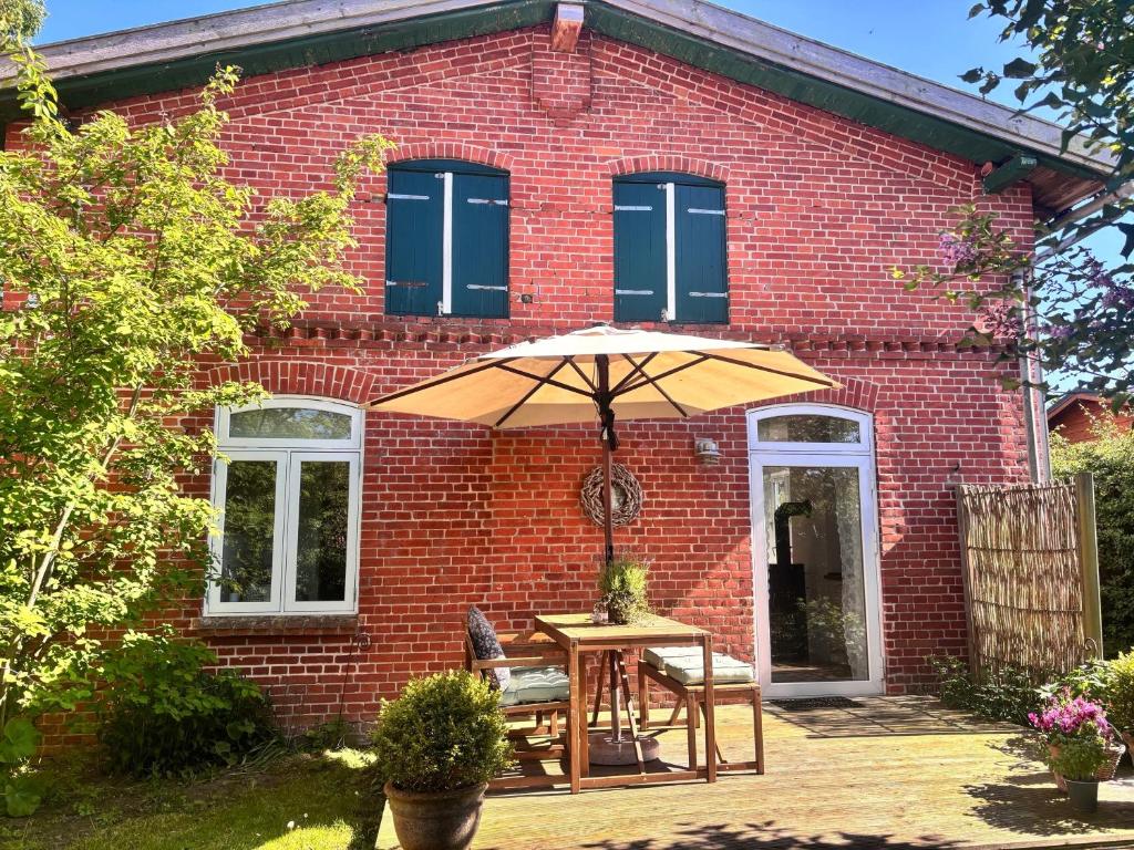 a brick house with a table and an umbrella at Ferienwohnung Zeitweise in Bünsdorf am Wittensee in Bünsdorf