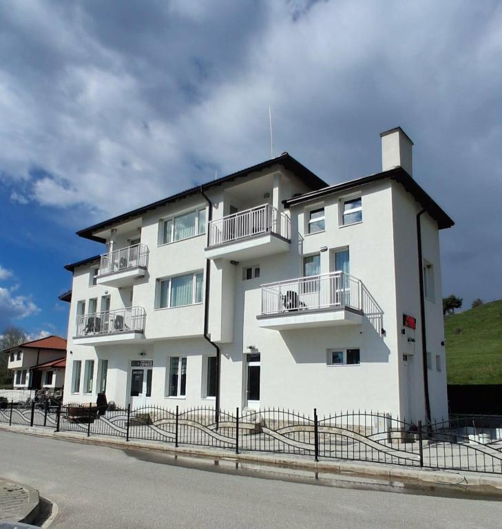 a white building with balconies on the side of it at Къща за гости Орфей in Dospat
