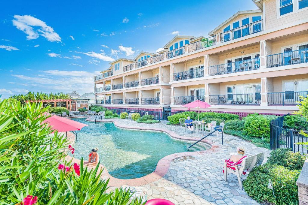 a resort with a swimming pool with people sitting in chairs at Good Trouble - Croatan Surf Club, Ocean View, Indoor and Outdoor Pool, Hot Tub, Pets Ok, YR Flex in Kill Devil Hills