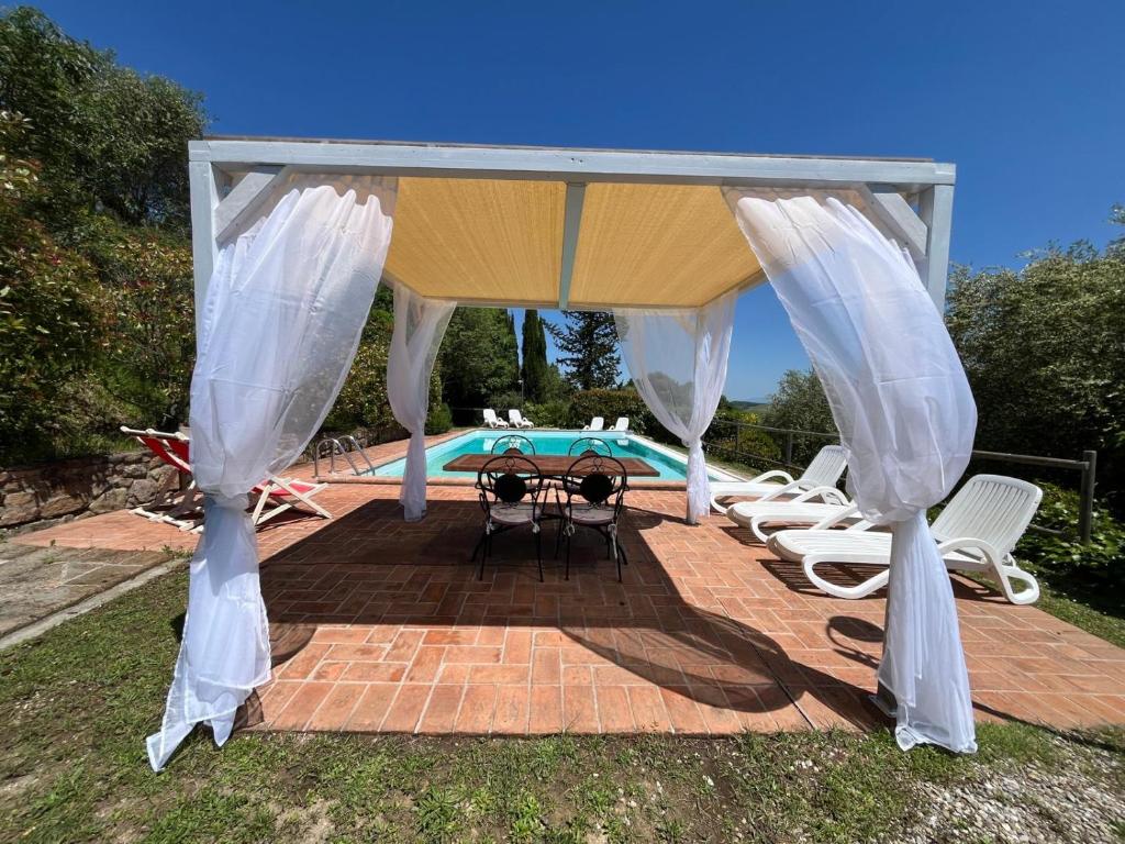 a pavilion with chairs and a table and a pool at Villa Ledonia in Montaione
