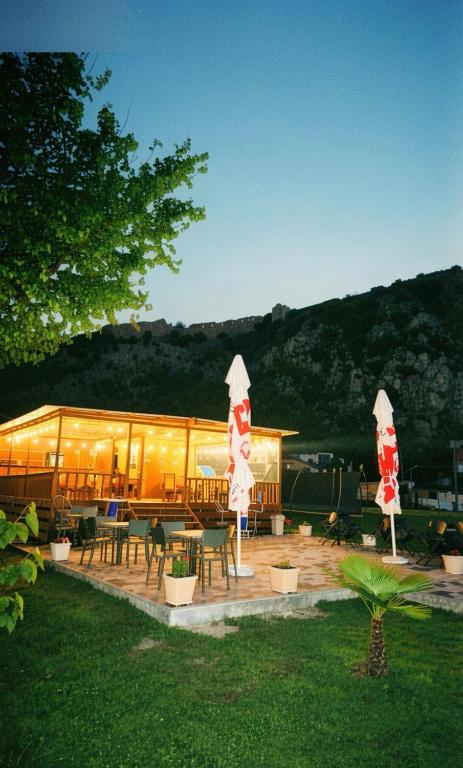 a building with tables and chairs in a yard at Camping Two Rivers in Shkodër