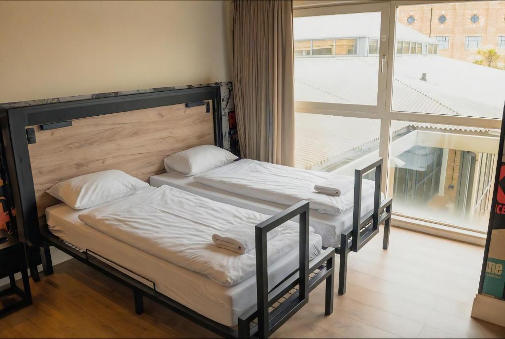 two beds in a room with a large window at a&o London Docklands Riverside in London