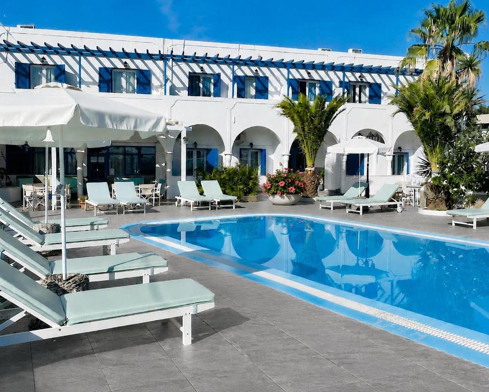 a swimming pool with chairs and a building at Villa Ilios in Fira