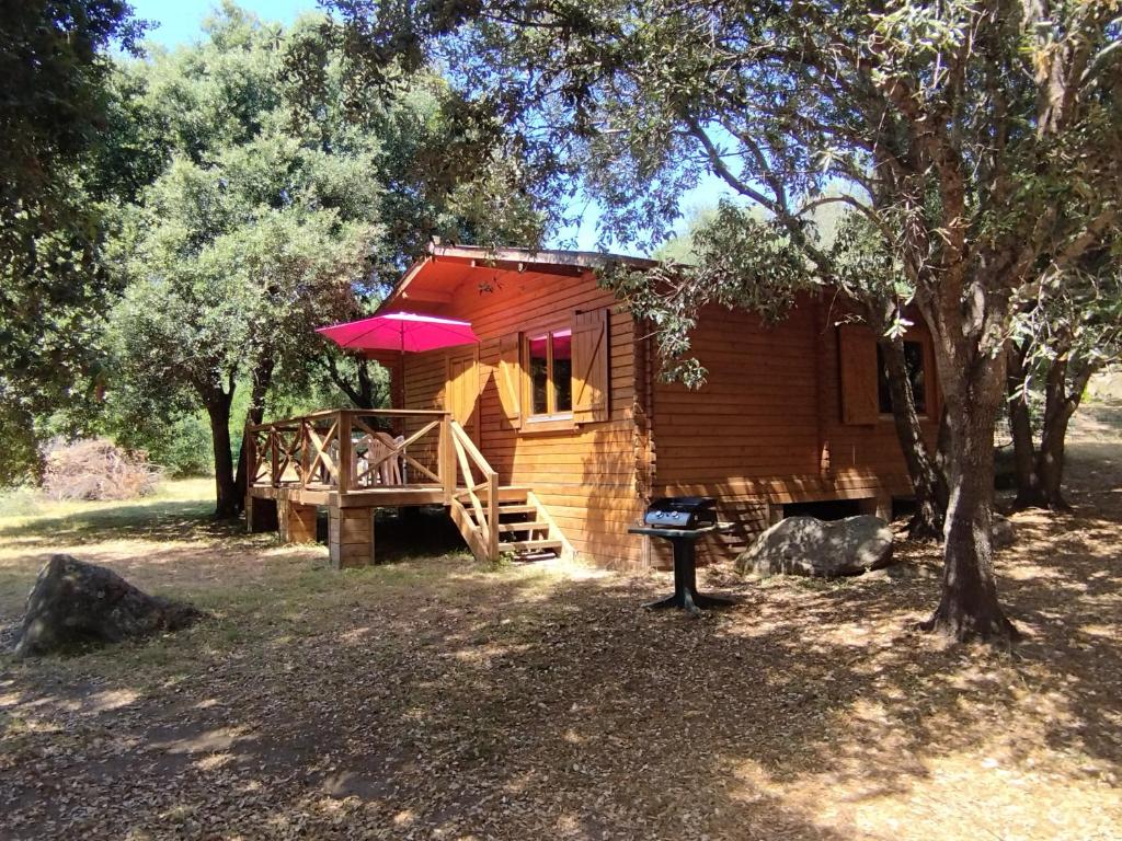 a wooden cabin with a porch and a tree at chalets bois 150m de la plage in Olmeto