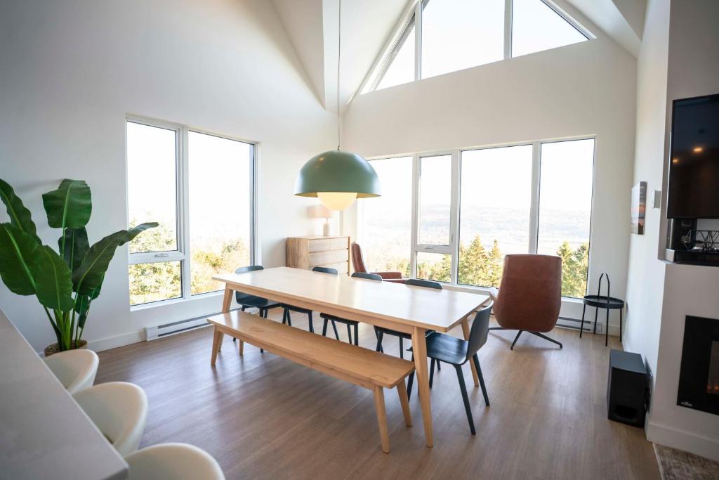 a dining room with a table and chairs and windows at 411 - Luxury Condo - Incredible View & Pool in Baie-Saint-Paul