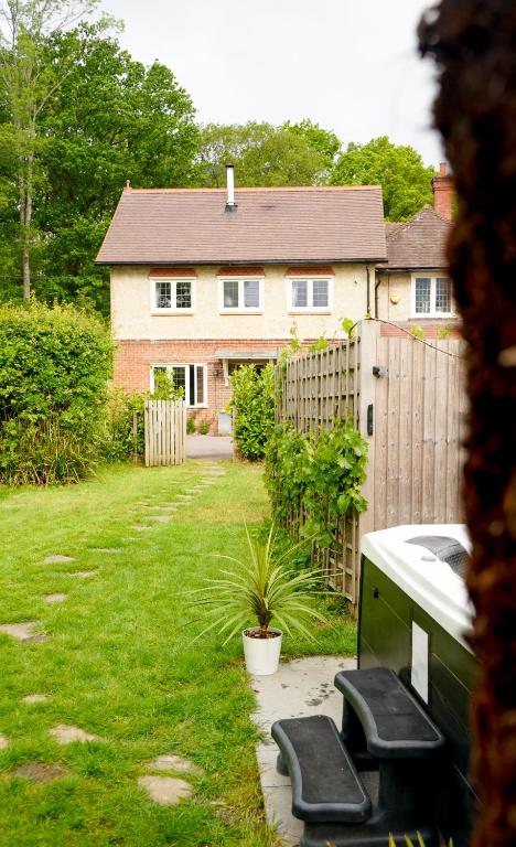 a house with a fence and two benches in a yard at Edwardian Cottage in beautiful surroundings with hot tub in Slinfold