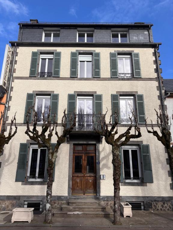 a building with trees in front of it at Résidence la Plage in La Bourboule