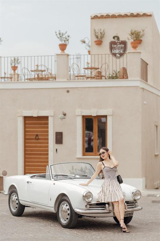 a woman in a dress standing next to a white car at Locanda delle rose in Roccavaldina
