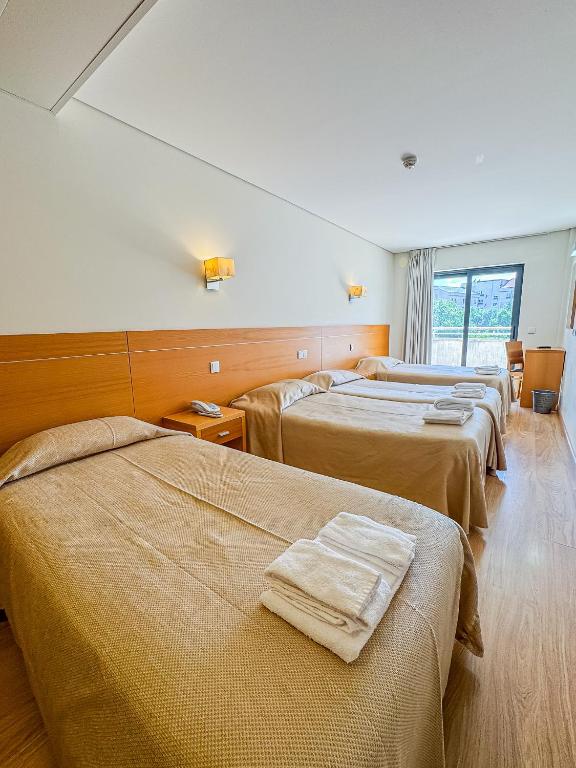 a hotel room with four beds with towels on them at Hotel 13 de Outubro By Umbral in Fátima