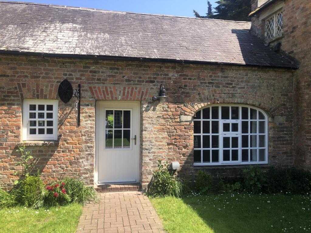 a brick house with a white door and windows at Wells House & Gardens Self Catering 3 Bedrooms & Sofa Bed Sleep8 in Glenranny