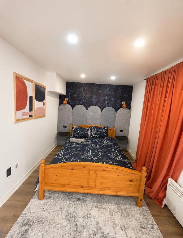 a bedroom with a wooden bed with an orange curtain at Respite room in Chambly