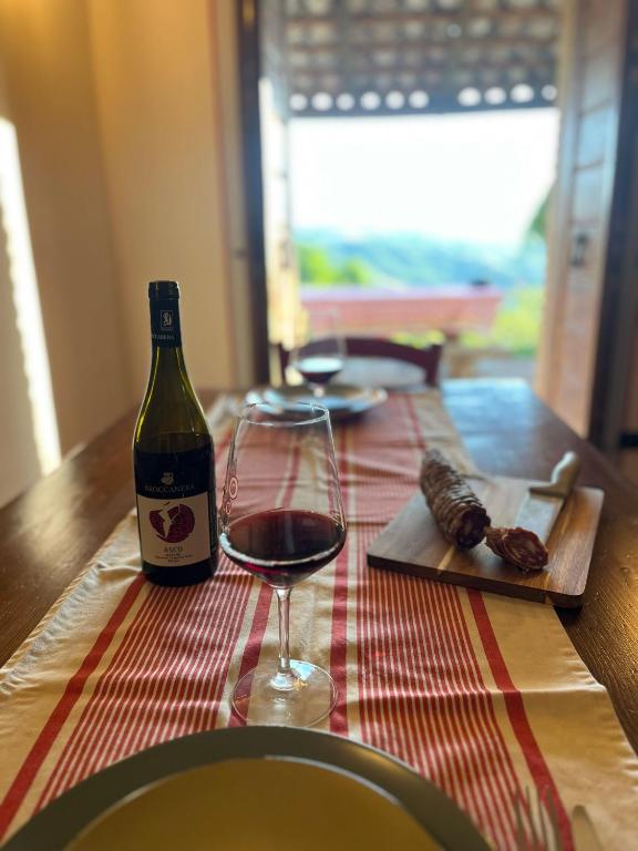 a bottle of wine and a glass on a table at Costa Alta - Casa Vacanze in Arcevia