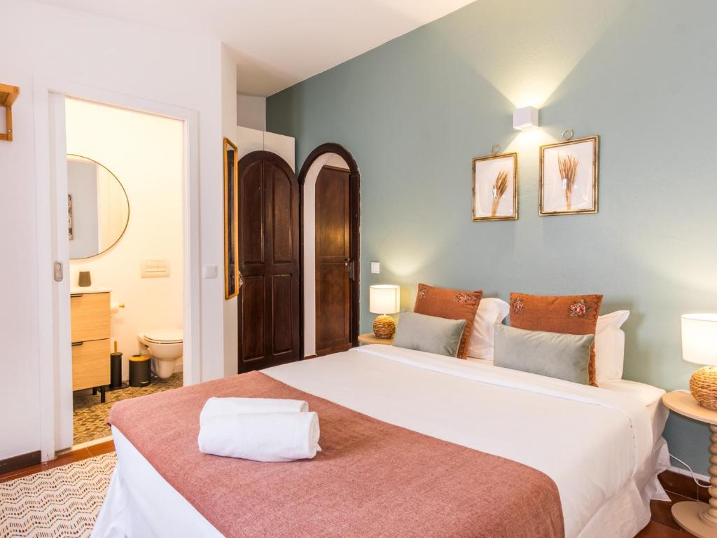 a bedroom with a large white bed and a bathroom at Foral Guest House in Óbidos
