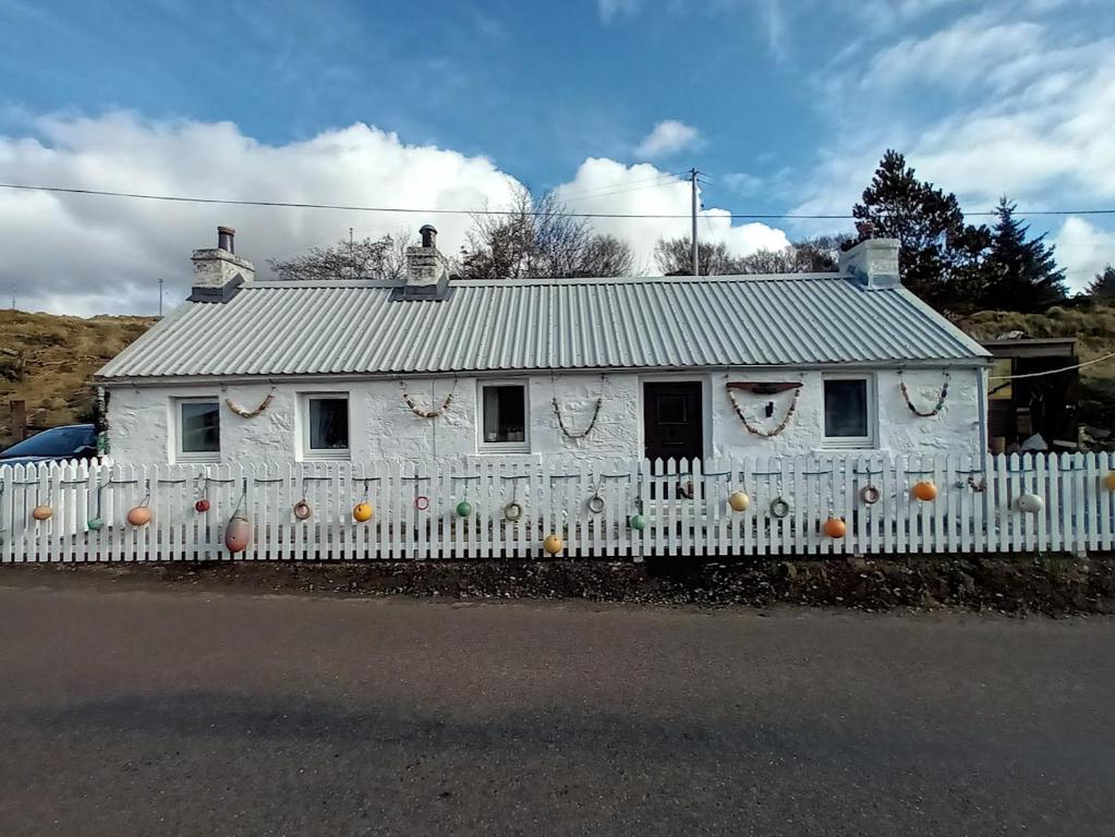a white house behind a white picket fence at The Captains in Bettyhill