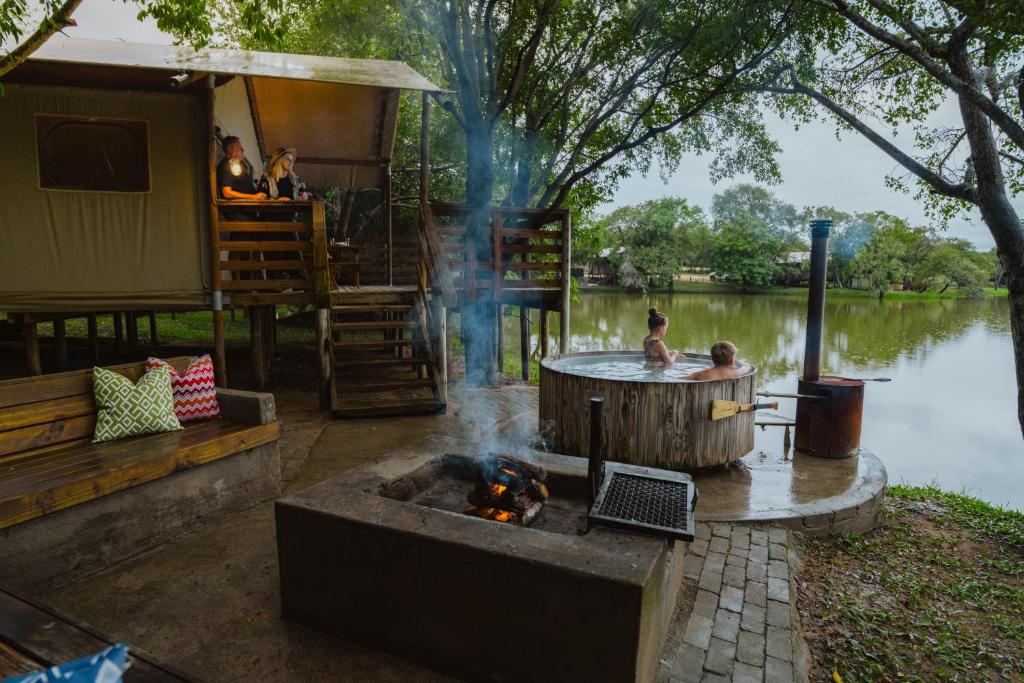 a group of people bathing in a hot tub next to a lake at AfriCamps Hoedspruit in Hoedspruit