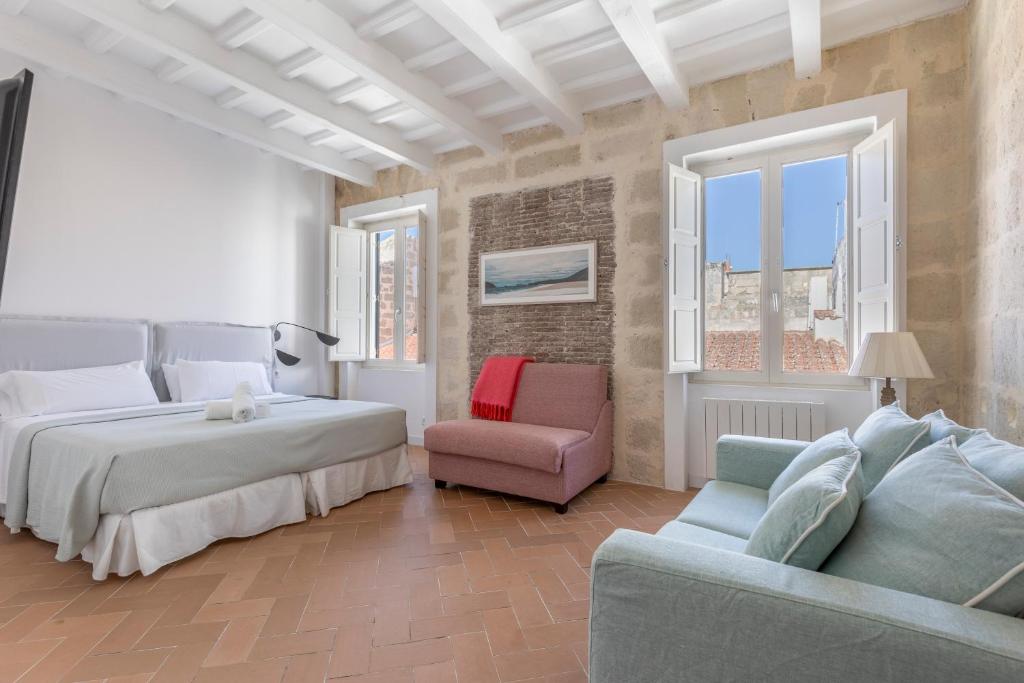 a bedroom with a bed and a chair and a couch at Suite 3 in Mahón