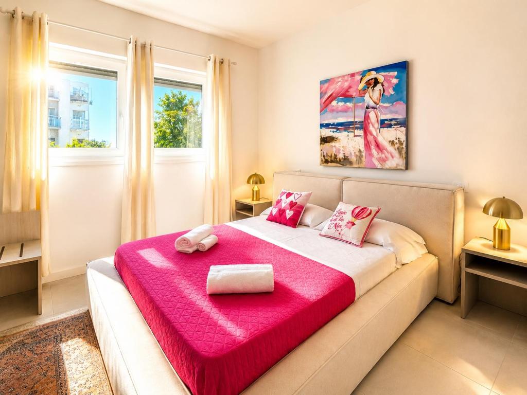 a bedroom with a large bed with a pink blanket at Villa Greif Apartment in Lignano Sabbiadoro