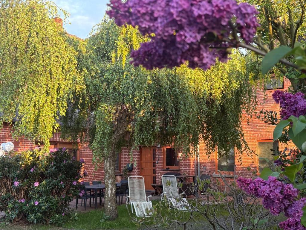 a brick building with a table and chairs under a tree at Am Storchennest in Walsrode
