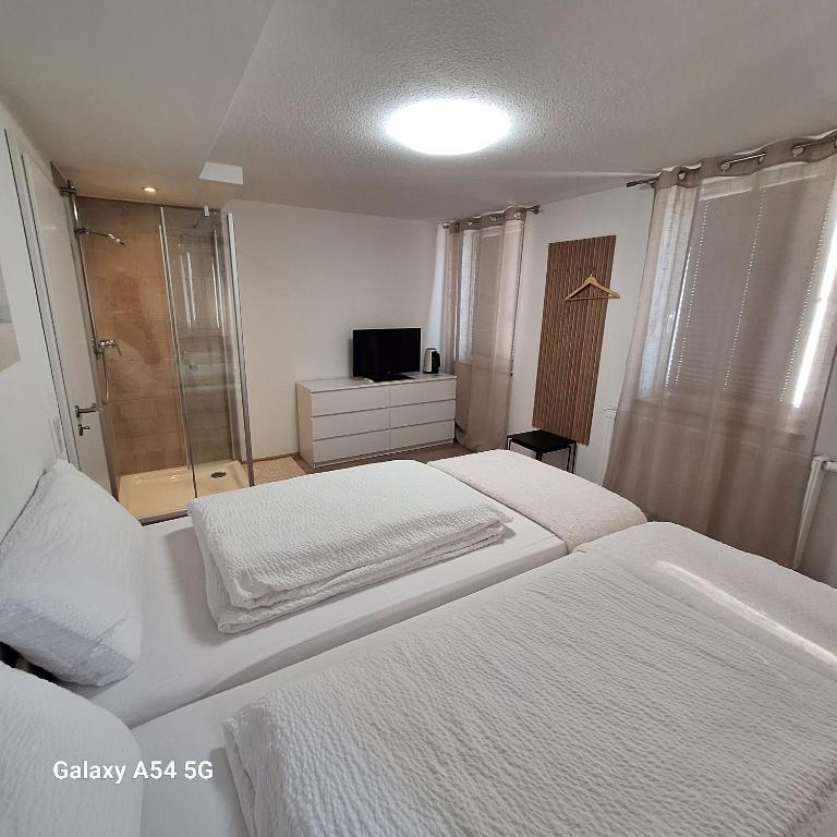 a white bedroom with two beds and a television at Gasthaus Sonne 3 in Braunsbach