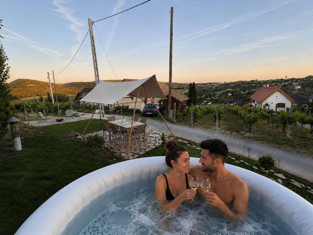 a man and woman drinking wine in a hot tub at Szőlők közt Apartman in Dunaszentmiklós
