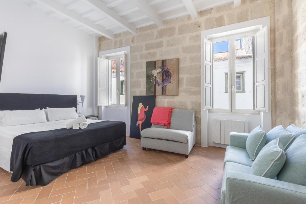 a bedroom with a bed and a couch and a chair at Suite 2 in Mahón
