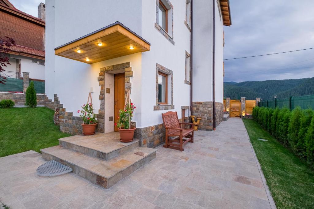 a patio with a chair and a house at Chalet BOGEMA - Sauna, BBQ & Jacuzzi in Beli Iskar