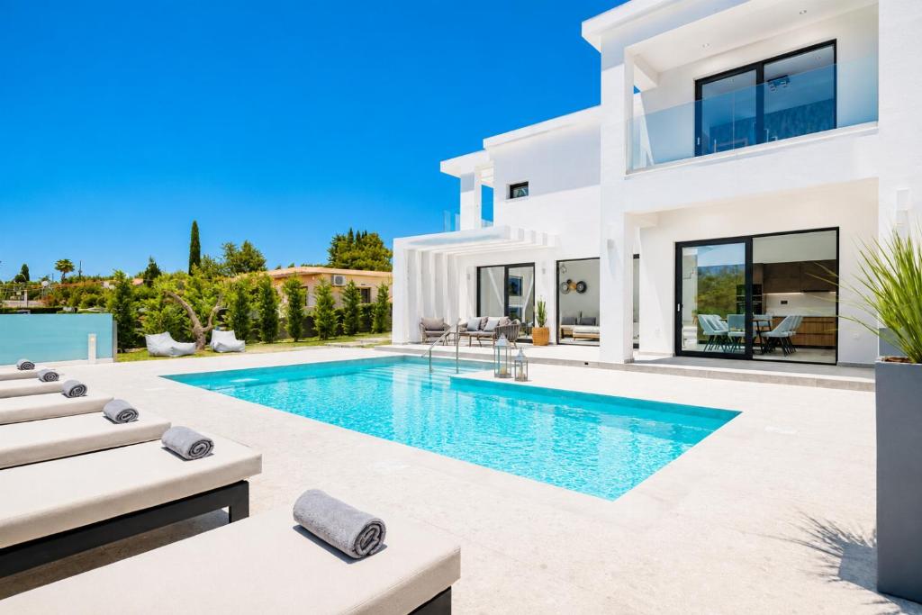 a white villa with a swimming pool and lounge chairs at Villa Vatia 3 in Tragaki