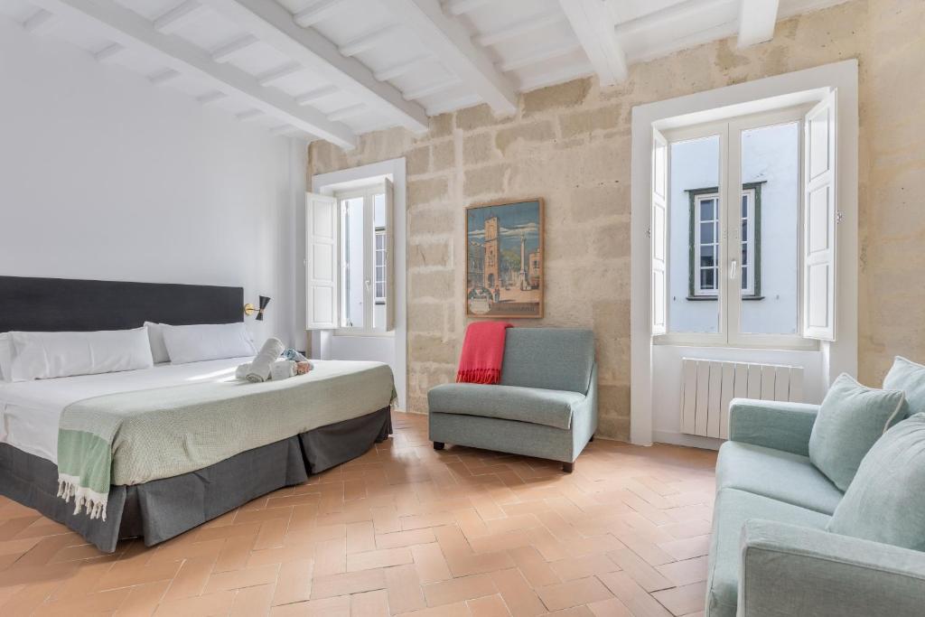ein Schlafzimmer mit einem Bett, einem Stuhl und einer Couch in der Unterkunft Suite 1 in Maó