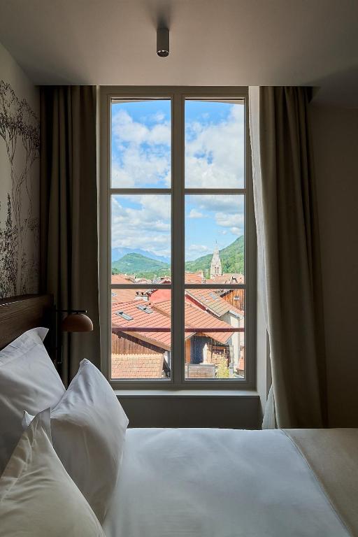 a bedroom with a bed and a large window at Le Parc - Hôtel & Spa in Allevard