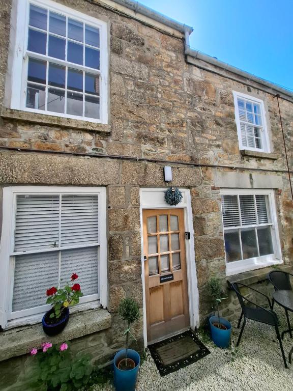a brick building with a door and two windows at The Mews Cottage in Penzance