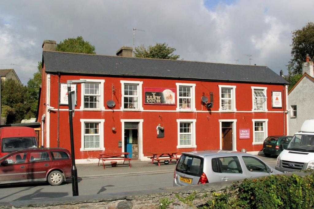 a red building with cars parked in front of it at Y Llew Coch Tregaron in Tregaron