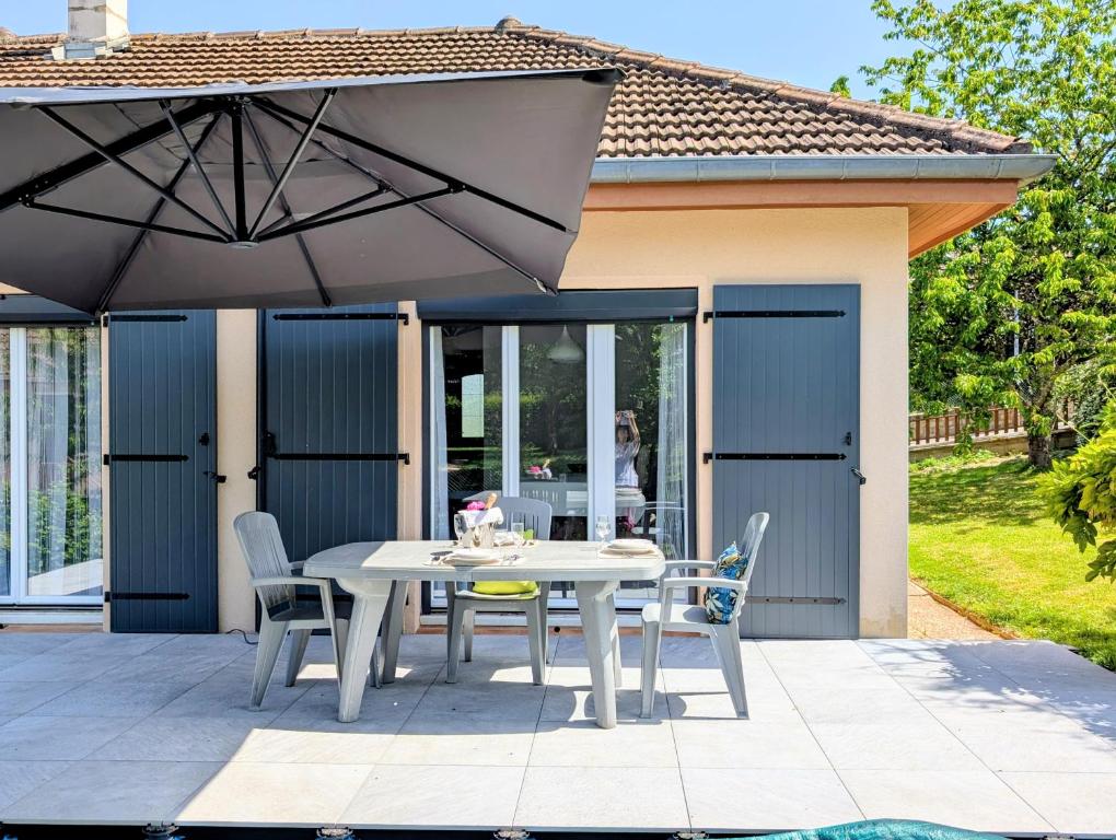 a table and chairs under an umbrella on a patio at VILLA climatisée - 4 étoiles - 75 m2 avec Jardin pour 3 personnes - à 10 min de Besançon in Dannemarie-sur-Crête