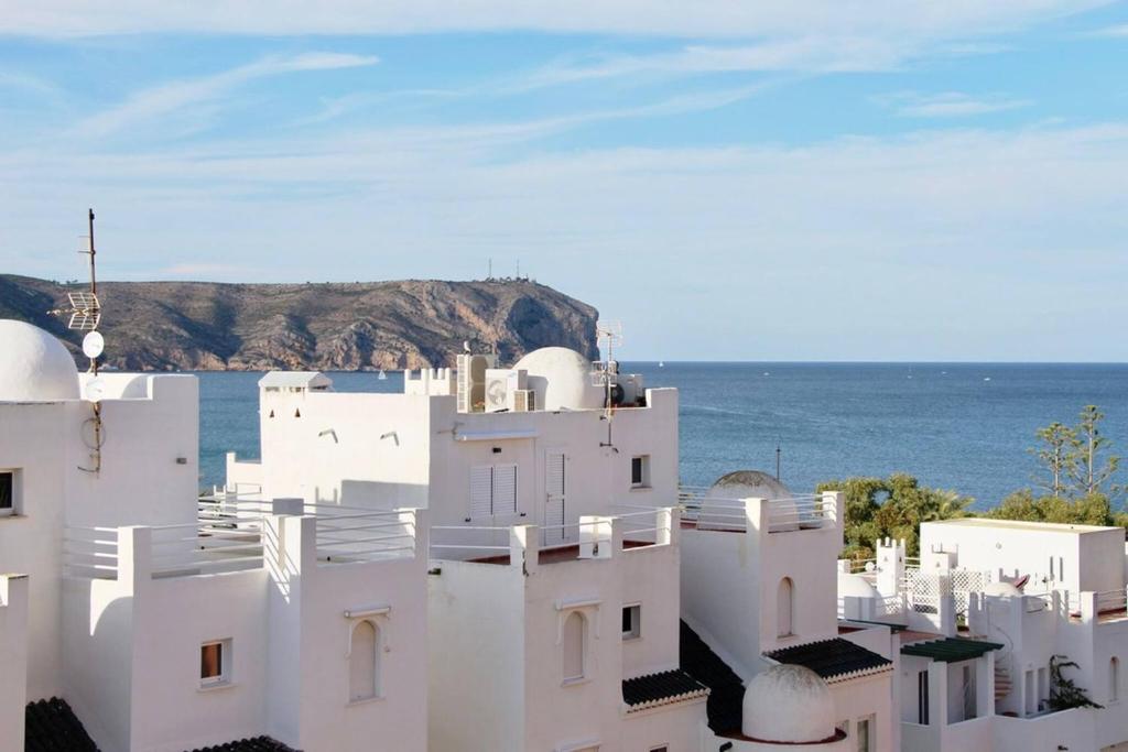 a white building with the ocean in the background at Golden Paradise 75 by homeprive in Jávea