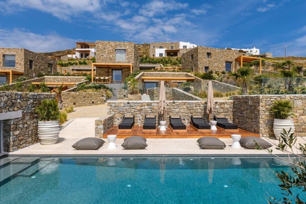 a villa with a swimming pool in front of a building at Panormos Bay Suites Luxury Resort in Mikonos