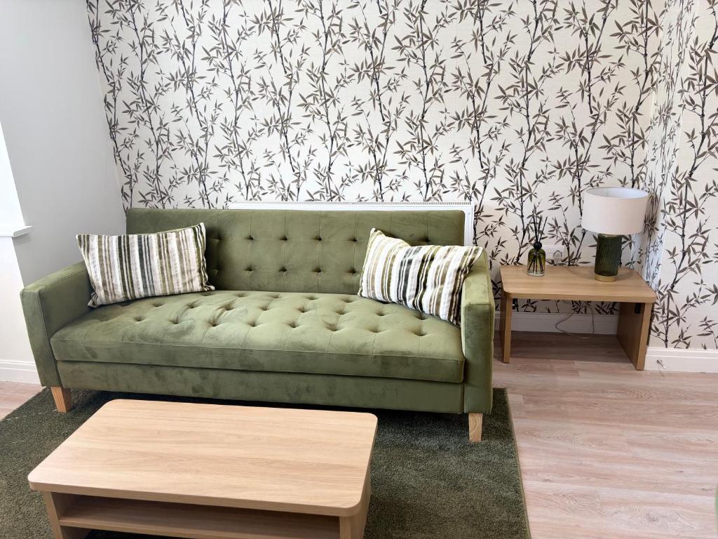 a green couch in a living room with a wallpaper at St Marks Court Apartments in Anlaby