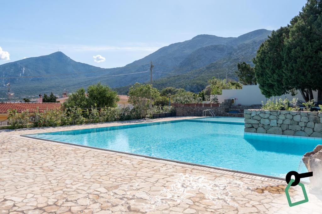 a swimming pool in a house with mountains in the background at Hotiday Cala Gonone in Cala Gonone