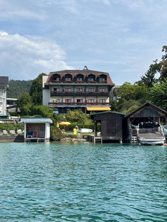 a large building sitting on the water next to a building at Hotel Garni Vindobona in Pörtschach am Wörthersee