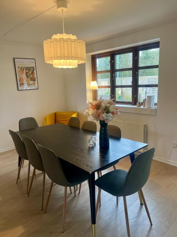 a dining room table with chairs and a vase with flowers at Cozy house with garden in Odense