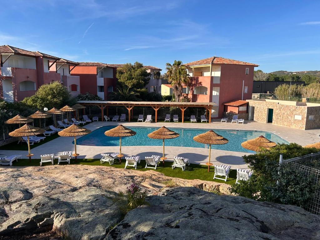a swimming pool with chairs and umbrellas at Hôtel Maristella in Algajola