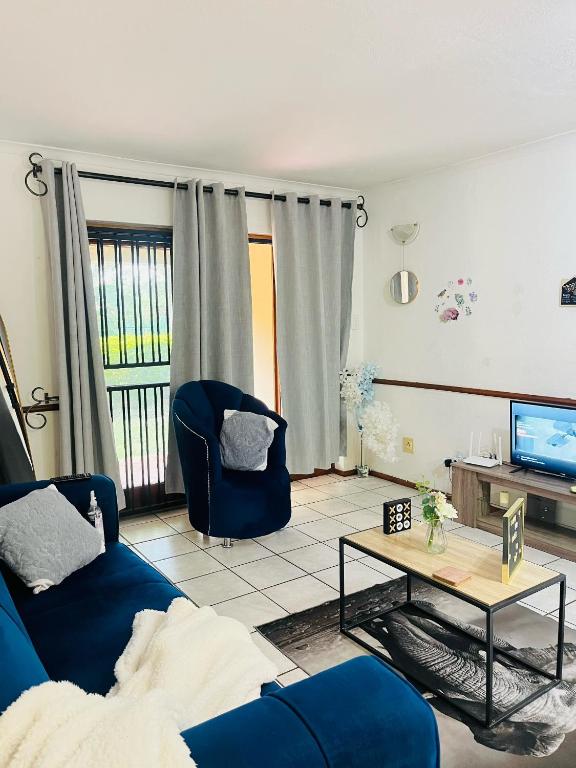 a living room with a blue couch and a table at Intsika apartments in Nelspruit
