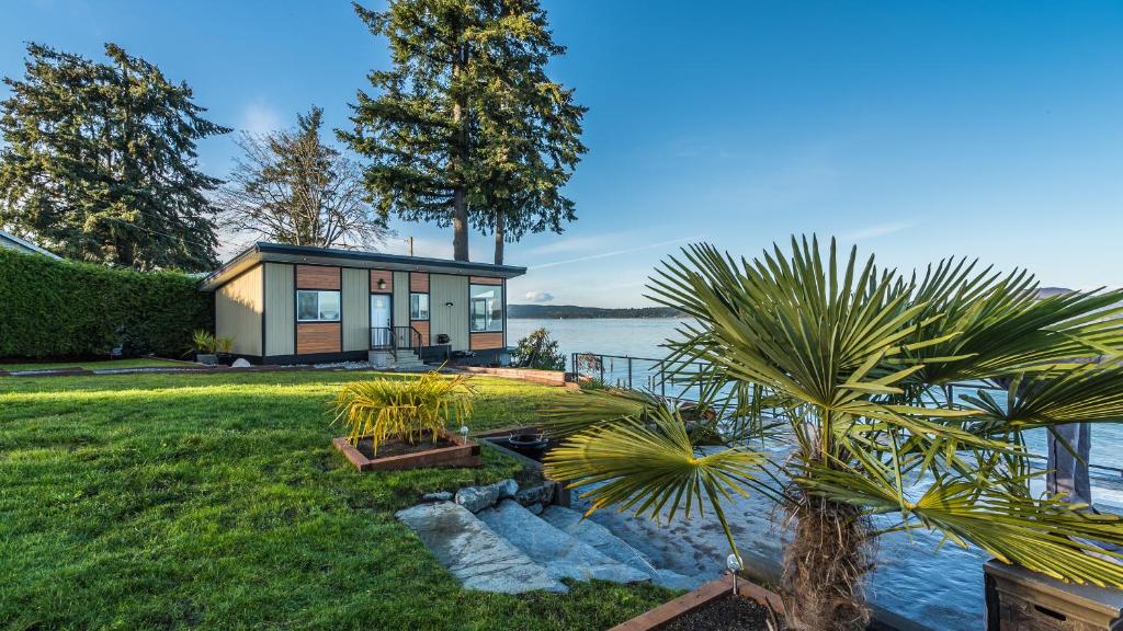 a small house with a palm tree in front of the water at Sunrise Terraces in Ladysmith