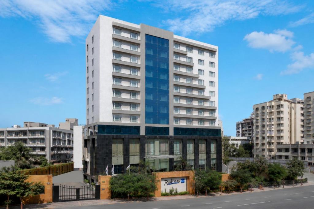 a tall white building in a city at Radisson Blu Hotel Ahmedabad in Ahmedabad
